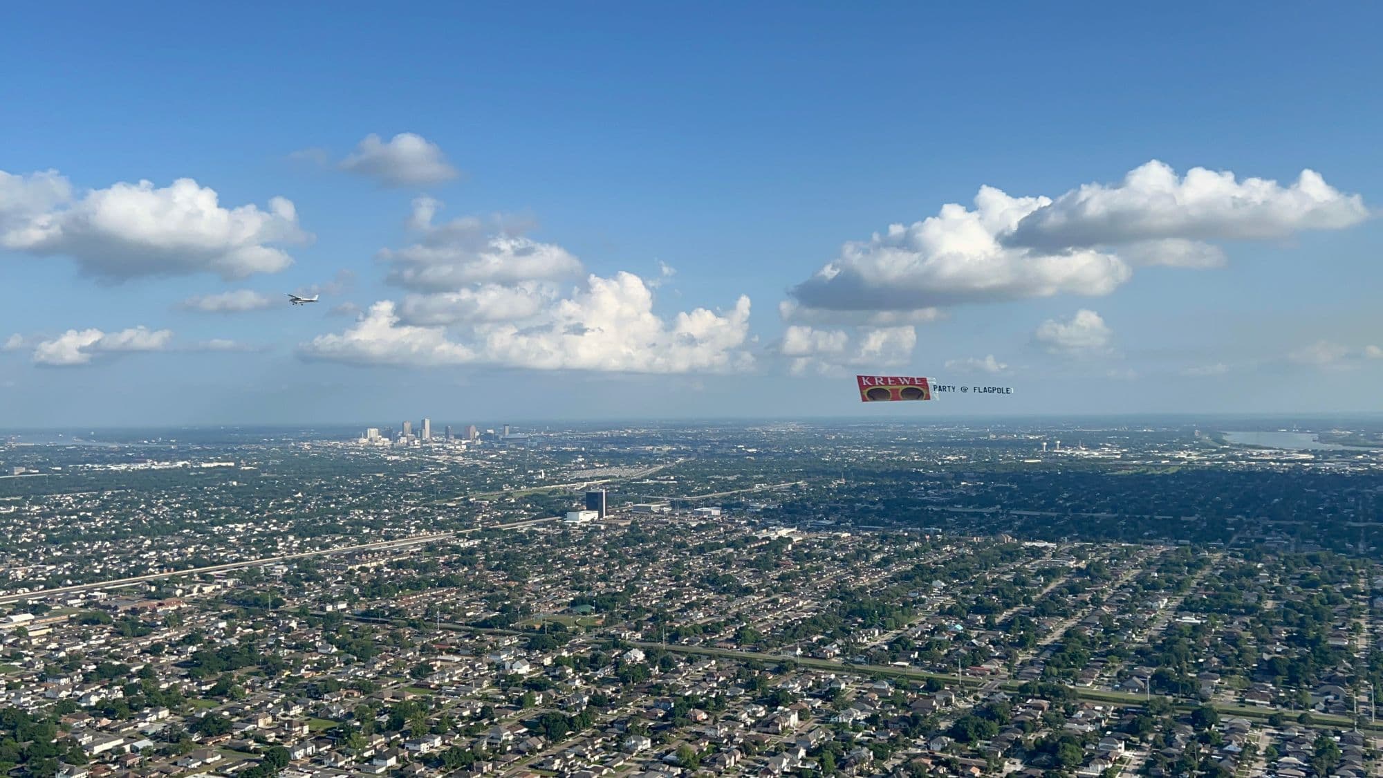 Aerial banner in tow over New Orleans neighborhoods with the downtown skyline ahead
