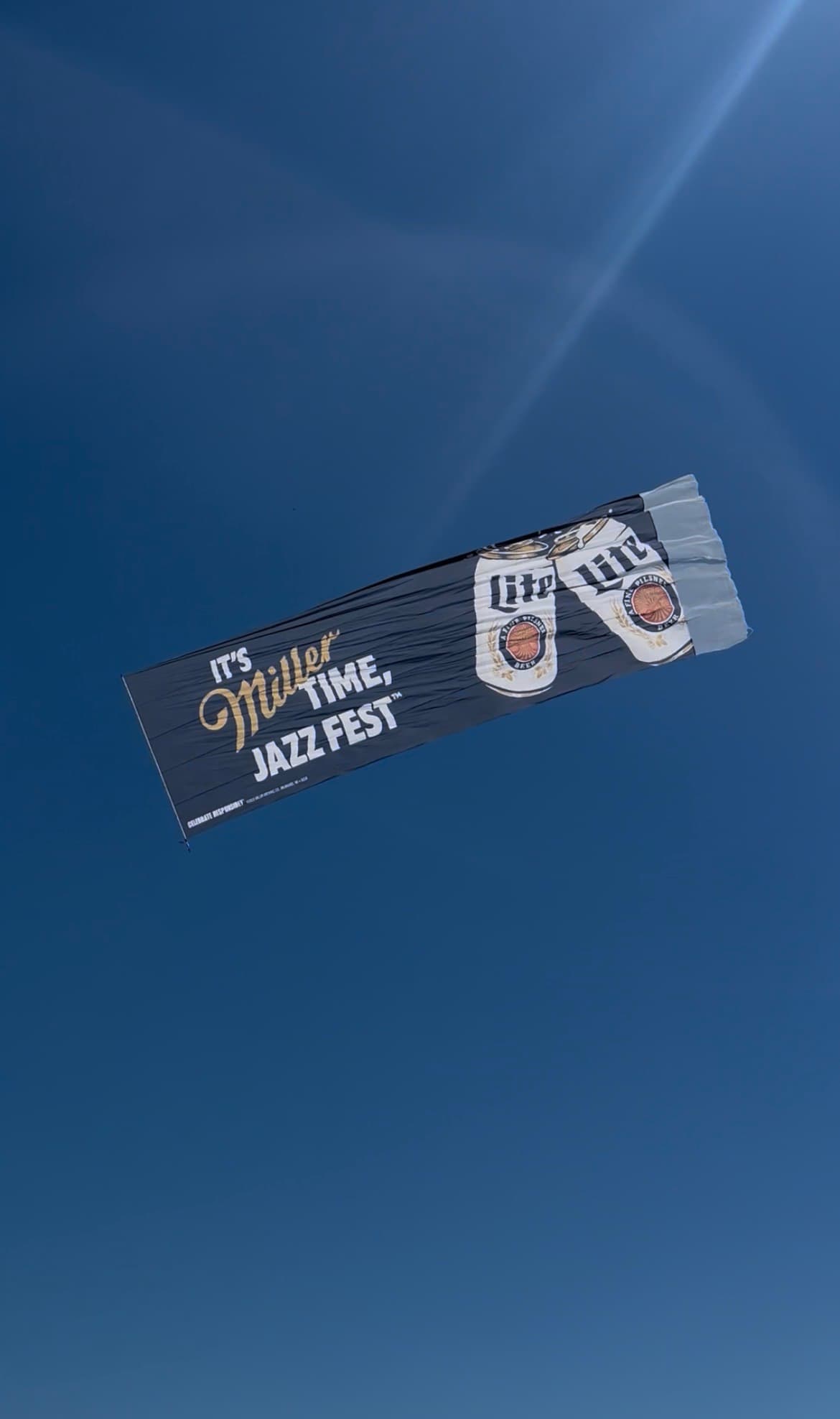 Miller Lite aerial banner reading It's Miller Time, Jazz Fest in flight over New Orleans